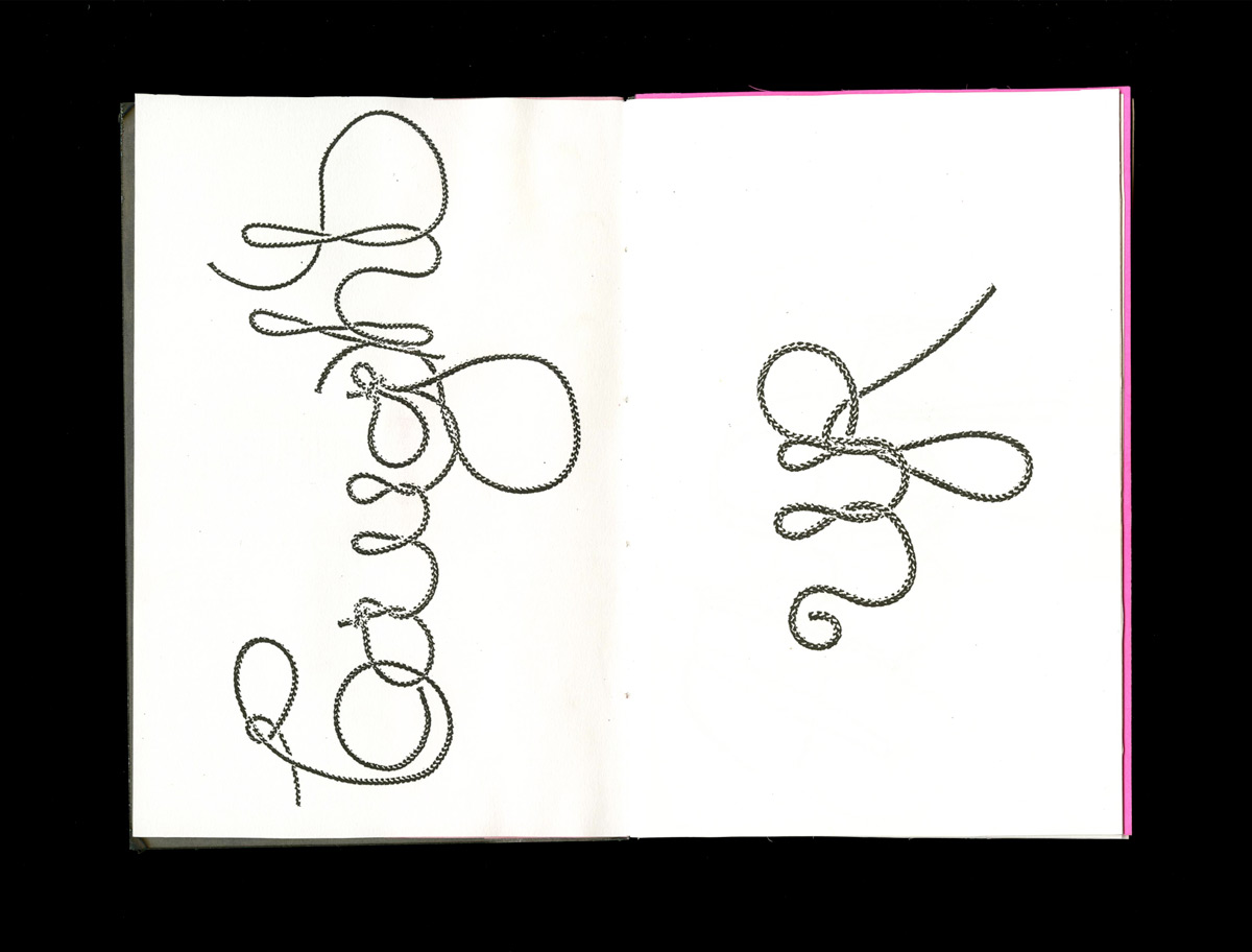 open book spread displaying the word 'caught' and 'up' in a typeface made of rope on the left and right pages, respectively, on a white paper